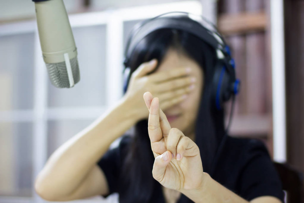 Micrófono en estudio con mujeres asiáticas borrosas hacer símbolo de dedo o
 - Foto, imagen
