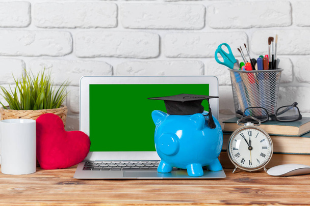 Piggy money box with laptop on wooden table - 写真・画像