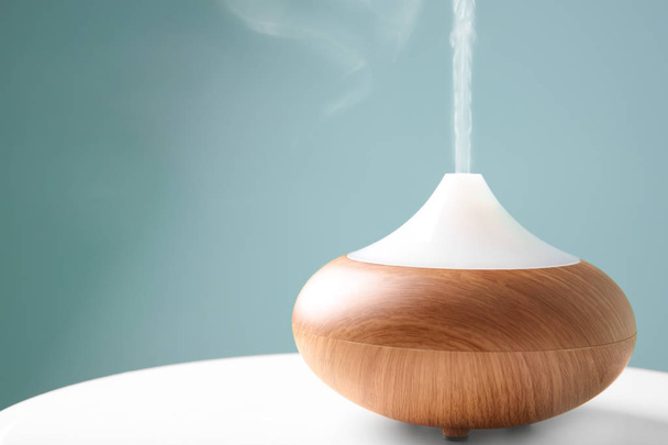 Aroma oil diffuser on table against color background - 写真・画像