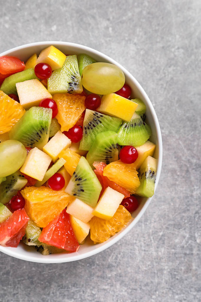 Bowl tuoreita hedelmiä salaatti harmaalla pohjalla
 - Valokuva, kuva