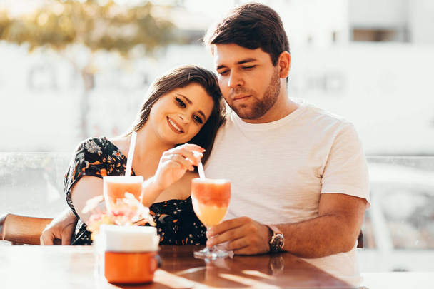 Young couple in love sitting in a restaurant, drinking colorful drink, having a conversation and enjoying the time spent with each other - Foto, immagini