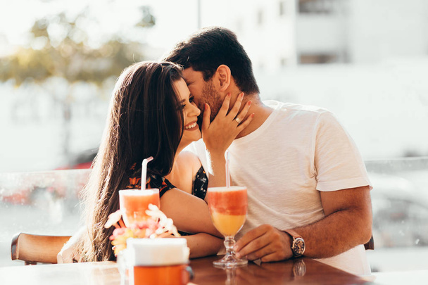 Young couple in love sitting in a restaurant, drinking colorful drink, having a conversation and enjoying the time spent with each other - 写真・画像