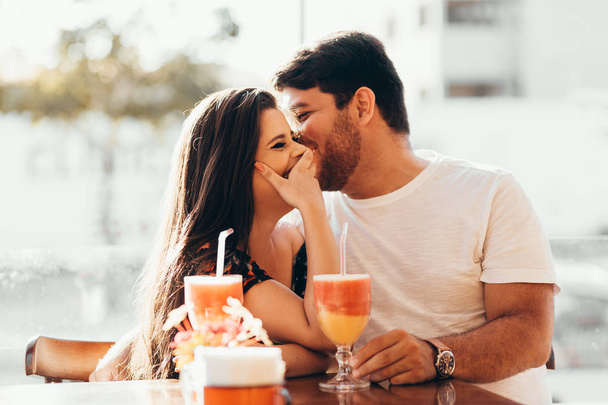 Jovem casal apaixonado sentado em um restaurante, bebendo bebida colorida, tendo uma conversa e aproveitando o tempo passado uns com os outros
 - Foto, Imagem
