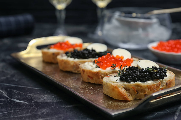 Sandwiches con caviar negro y rojo en bandeja
 - Foto, Imagen