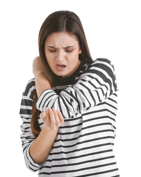 Mujer joven que sufre de dolor de codo sobre fondo blanco
 - Foto, Imagen