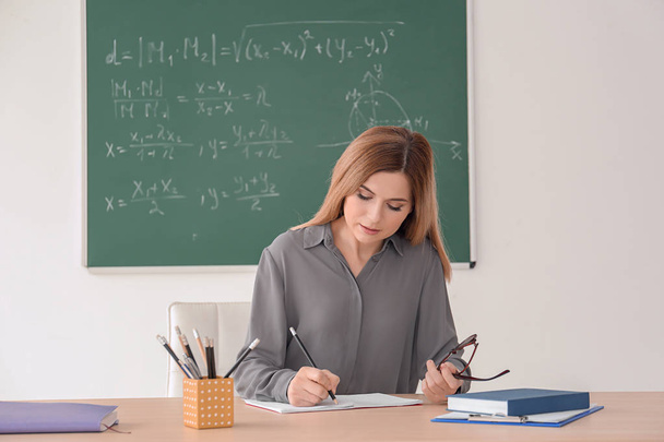 Young female teacher working at table in classroom - Photo, image