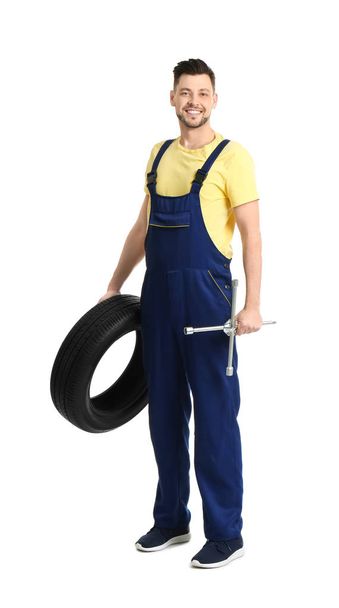 Male mechanic with car tire on white background - Photo, image