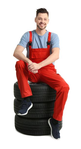 Male mechanic with car tires on white background - Zdjęcie, obraz