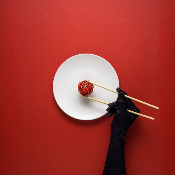 Creative concept photo of kitchenware with hand, painted plate with food on it on red background. - 写真・画像
