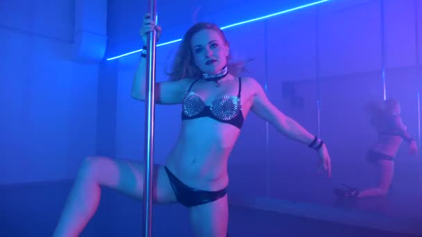 Young sexy slim woman pole dancing with pylon in dark interior - Materiał filmowy, wideo