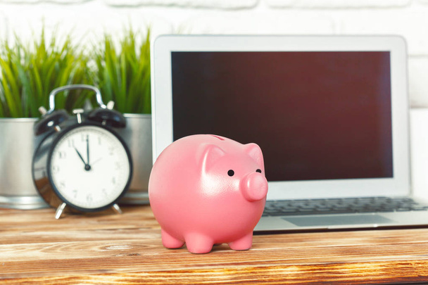 Piggy money box with laptop on wooden table - Foto, immagini