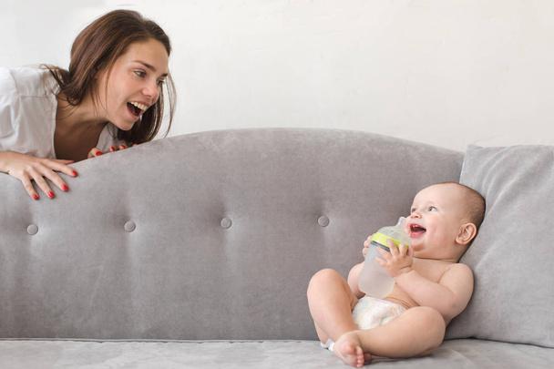 Mother and baby boy are playing on couch - Photo, image