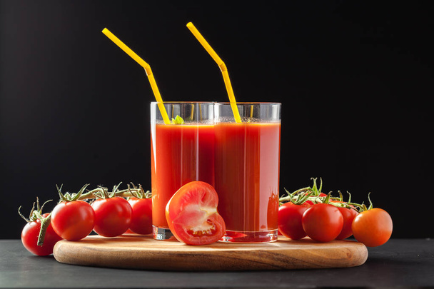 Tomato juice with tomatoes served in glass with straws - Foto, afbeelding