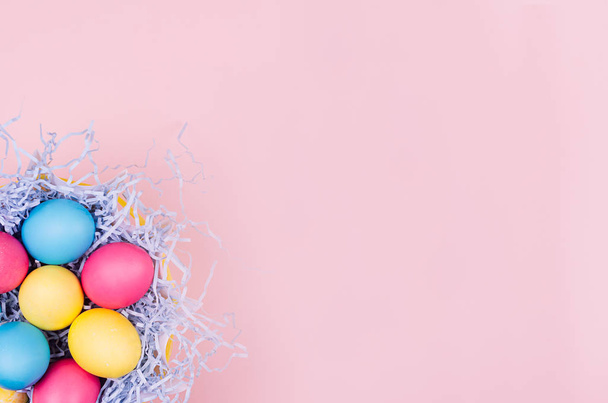 Easter colorful eggs in fun blue nest on soft pink background, copy space, top view. - Foto, Imagen