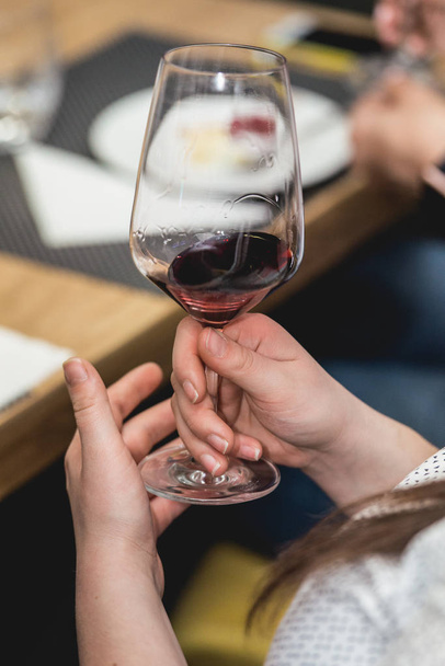 女性は、赤ワインのガラスを保持します。人は、ワインの色を考慮してどのように異なるガラスのにおいがします。 - 写真・画像