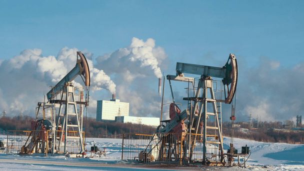 Рабочие насосы для добычи нефти на фоне нефтехимического завода
 - Фото, изображение