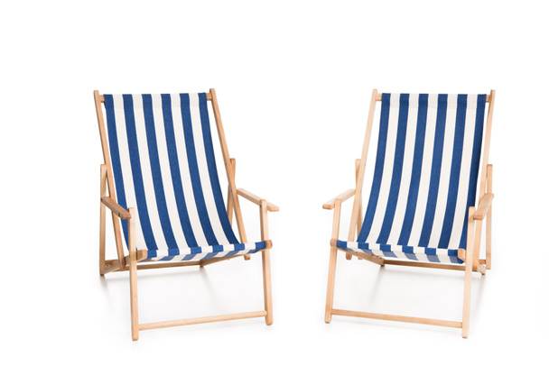 twee gestreepte strandstoelen, geïsoleerd op wit - Foto, afbeelding