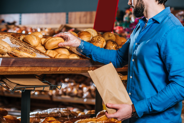 partial view of shopper taking loaf of bread in grocery shop - Fotoğraf, Görsel