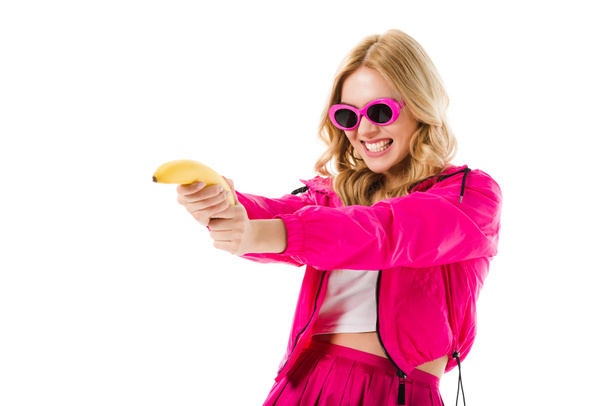 Young girl wearing pink shooting from banana isolated on white - Foto, imagen