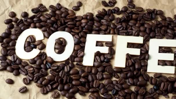 Φρυγμένους κόκκους καφέ σε χαρτί καφέ περιτυλίγματος. Η λέξη «καφέ" - Πλάνα, βίντεο