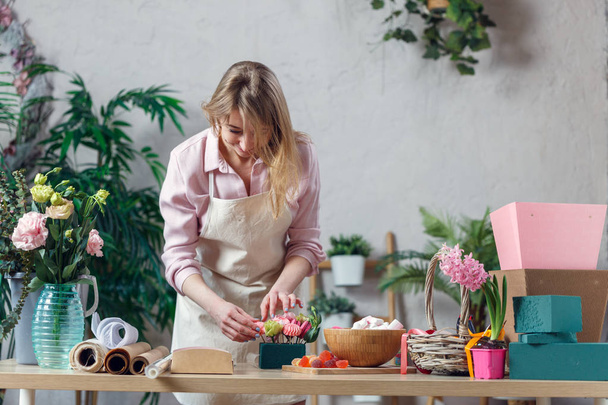 Image of blonde florist making composition of flowers - Photo, image