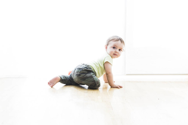 μωρό που μπουσουλάει στο πάτωμα με λευκό φόντο - Φωτογραφία, εικόνα