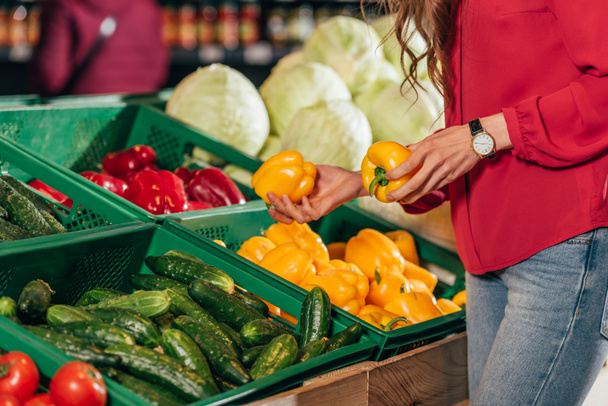 Partial view of shopper choosing fresh raw bell peppers in hypermarket - Foto, Bild
