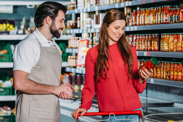 portrait of shop assistant in apron and female shopper in hypermarket - Foto, imagen
