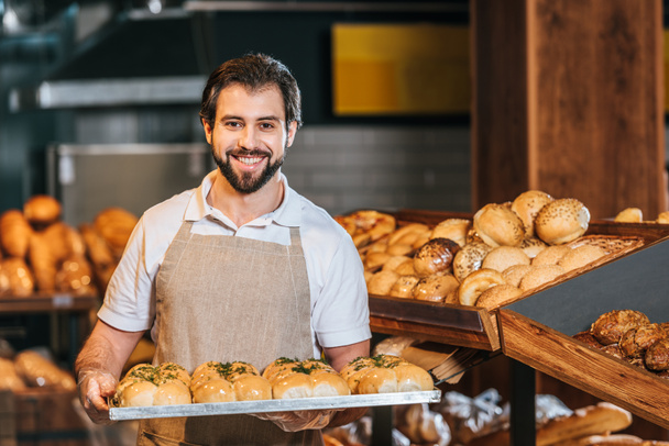portrait of smiling shop assistant arranging fresh pastry in supermarket - Fotoğraf, Görsel