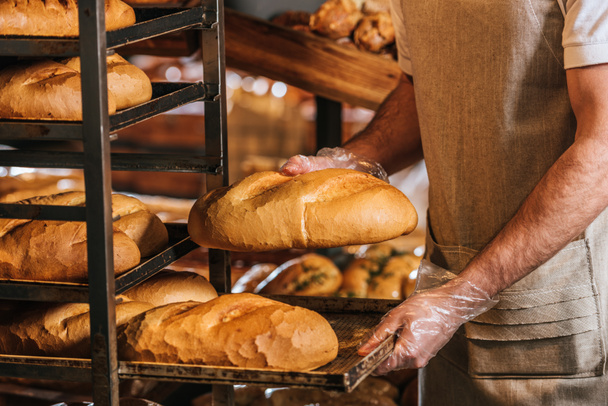 cropped shot of shop assistant arranging loafs of bread in supermarket - 写真・画像