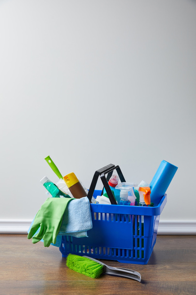 domestic supplies for spring cleaning in blue basket on floor - Fotoğraf, Görsel