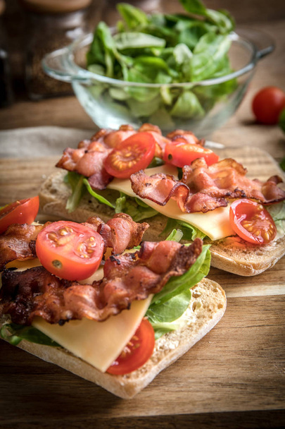 Ciabatta sandwich with arugula salad, bacon and yellow cheese. - Foto, Imagem