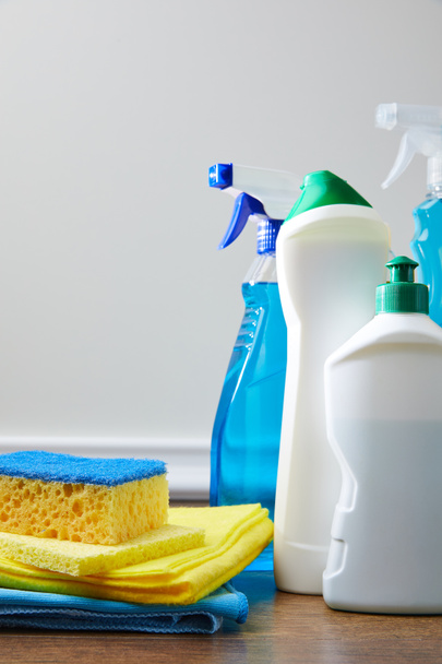 синяя и желтая губка, тряпки и бутылки для весенней уборки на полу
 - Фото, изображение