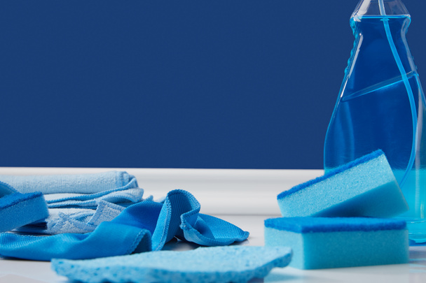 голубой спрей, тряпки и моющие губки для весенней уборки на полу
 - Фото, изображение