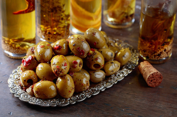 Spiced green olives and bottles with olive oil .  - Photo, image