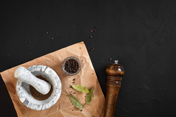 White mortar and pestle with dried peppers in flat lay on black background - Photo, Image