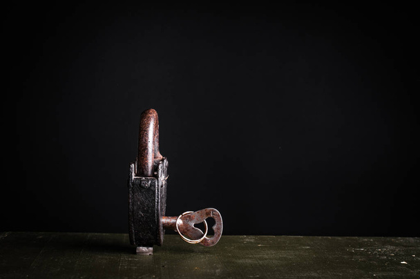 Ancient padlock with key isolated on black  - Foto, Bild