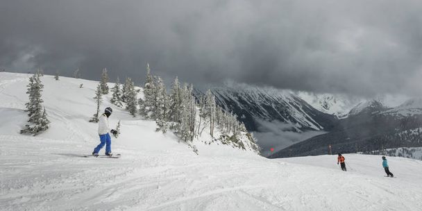 Туристы катаются на сноуборде и лыжах на снежных горах, Уистлер, Британская Колумбия, Канада - Фото, изображение