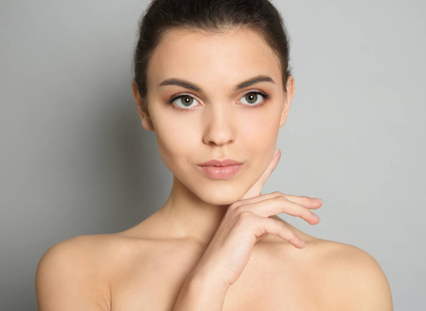 Young woman with beautiful makeup on grey background. Professional cosmetic products - Valokuva, kuva
