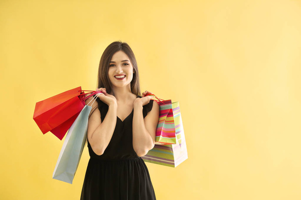 Beautiful young woman with shopping bags on color background - Zdjęcie, obraz