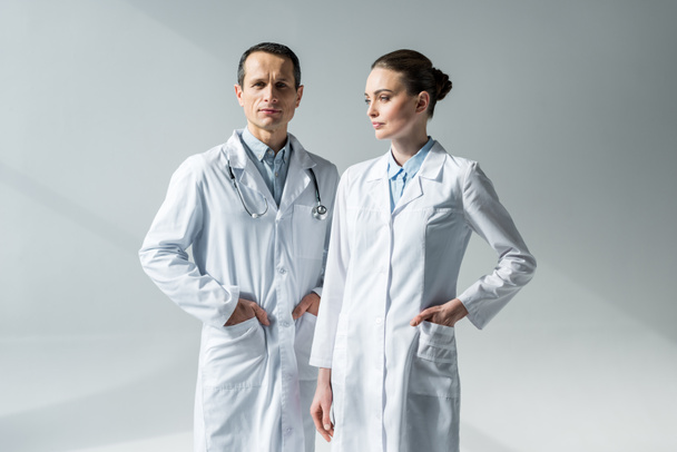 confident adult doctors in white coats on grey - Foto, Bild