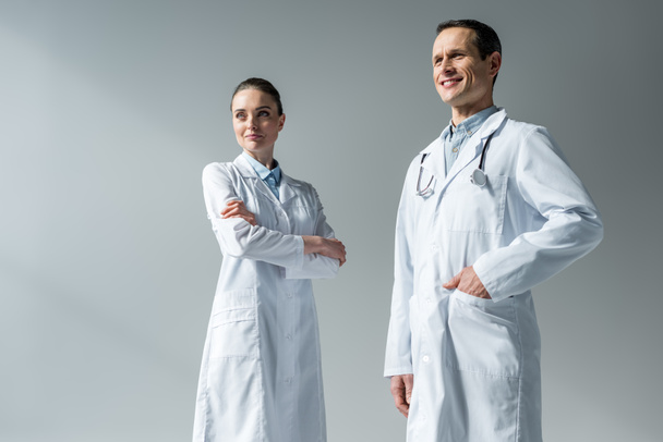 médicos adultos felices mirando hacia otro lado en gris
 - Foto, Imagen