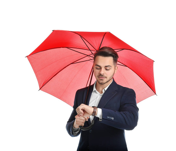 Young man in elegant suit with red umbrella on white background - Фото, изображение