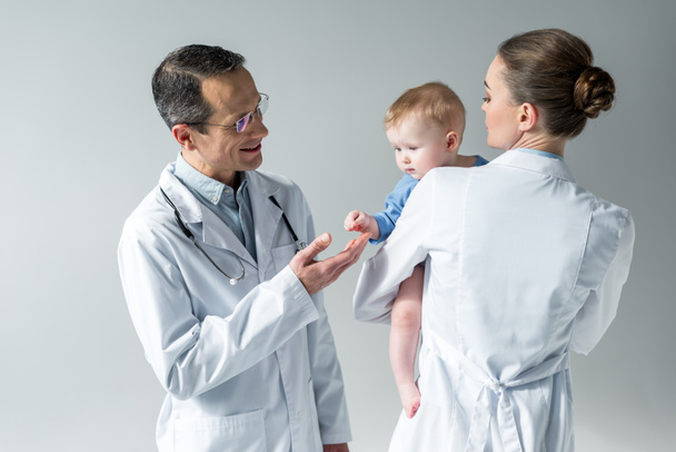 adult pediatricians with adorable little baby on grey - Фото, зображення