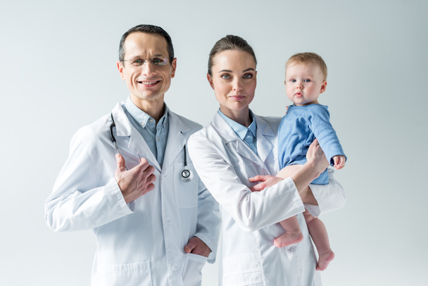 happy adult pediatricians with little baby on grey - Photo, Image
