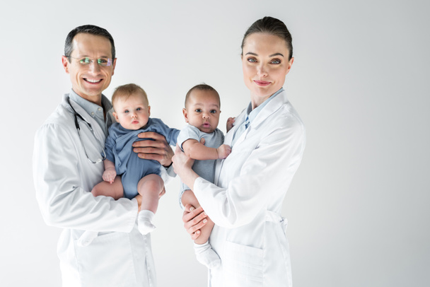 Lastenlääkärit, joilla on pieniä vauvoja ja jotka katsovat kameraa, joka on eristetty valkoisella
 - Valokuva, kuva