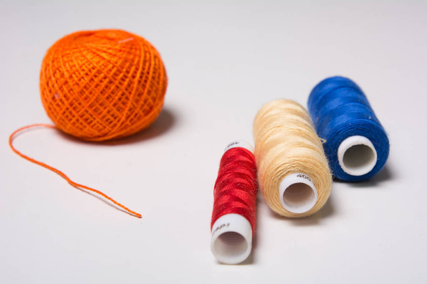 Three coils of multi-colored thread and a hank of orange - 写真・画像