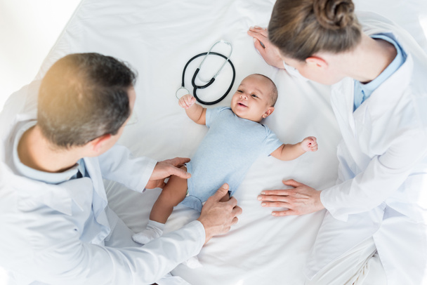 vista de ángulo alto de los pediatras jugando con el pequeño bebé en la cama
 - Foto, imagen