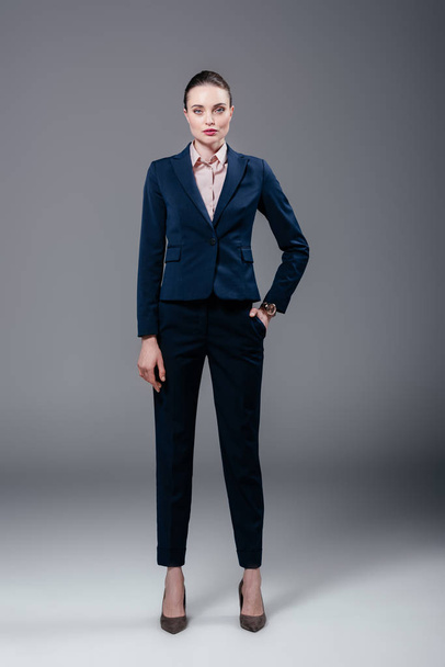 attractive adult businesswoman in stylish suit on grey - Фото, зображення