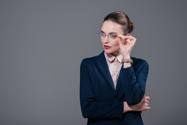 beautiful adult businesswoman in stylish suit and eyeglasses looking away isolated on grey - Fotoğraf, Görsel
